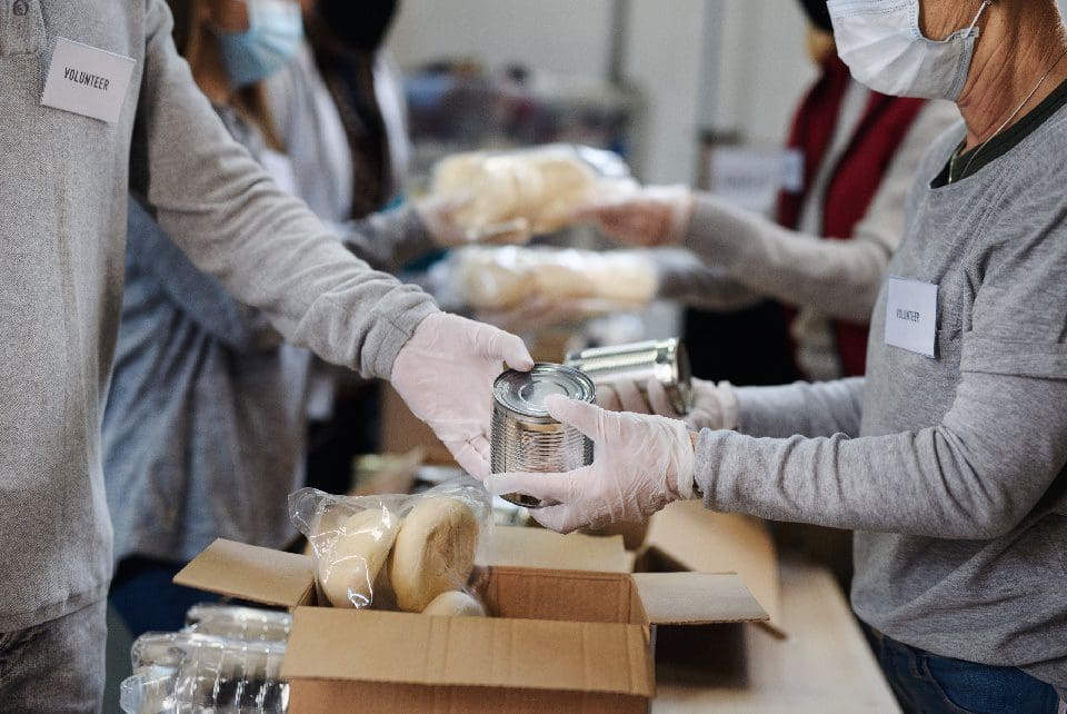 A group of people in gloves and masks preparing food.