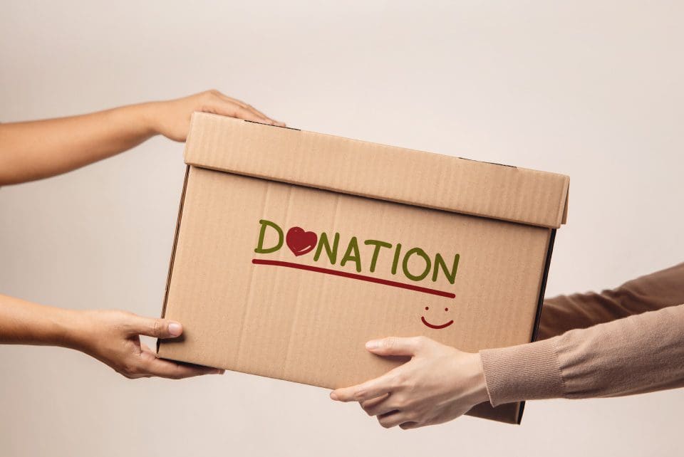 A person is handing someone a box with the word donation written on it.