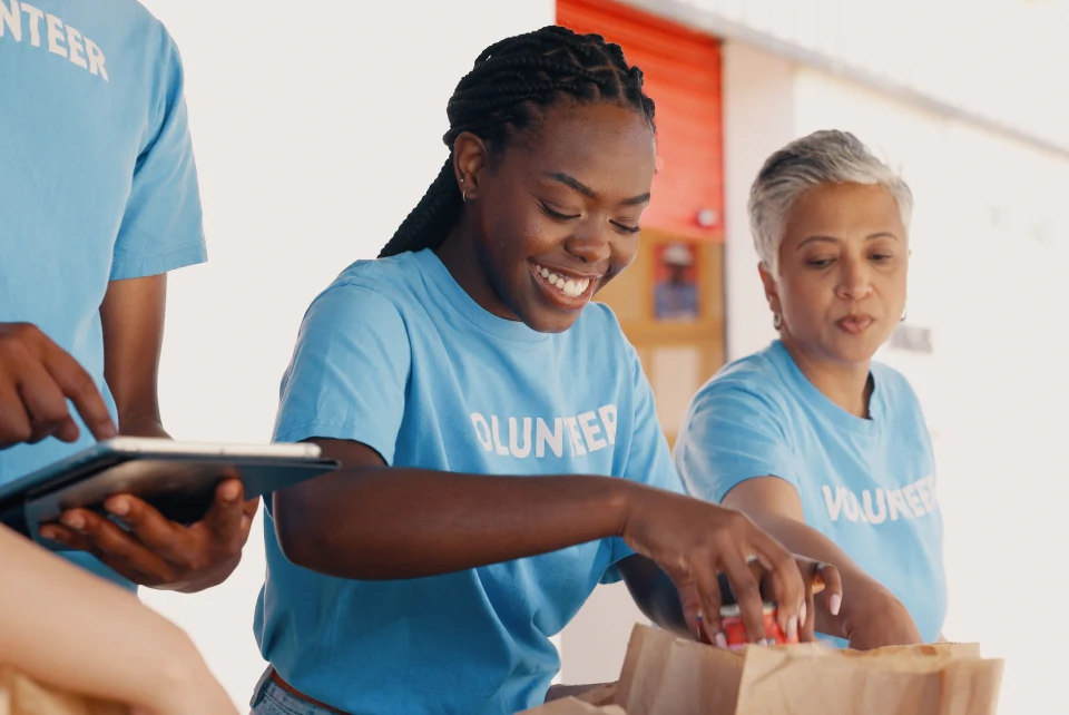 A woman in blue shirt cutting paper with another person.