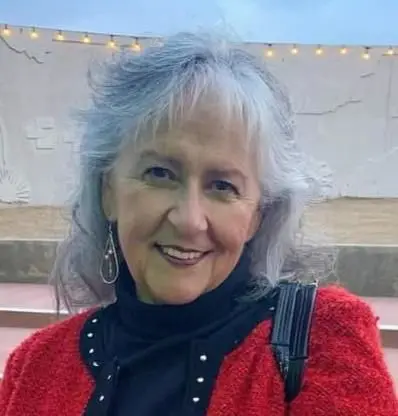 A woman with gray hair wearing red and black.